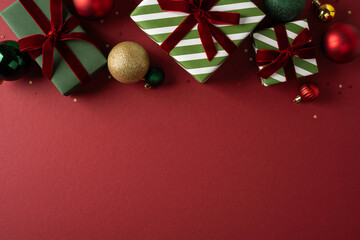 Fototapeta premium Festive Christmas presents and ornaments on red background with green striped wrapping and ribbons
