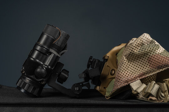Side view of tactical night vision monocular assembly connected to shroud on multicam skull cap on dark background