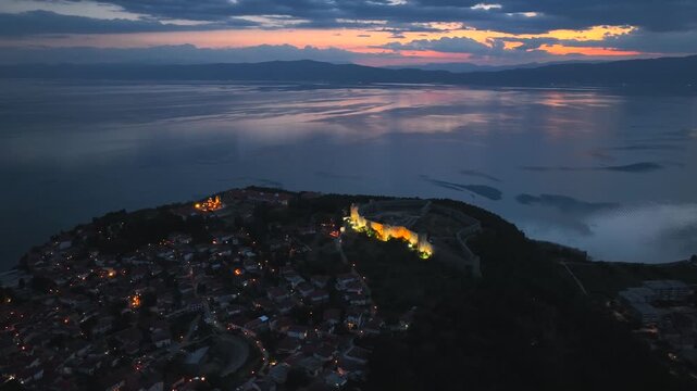 Aerial Twilight drone view of Ohrid City at Night in North Macedonia. Old Town on Ohrid lake with a beautiful fortress