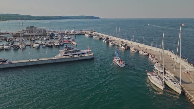 Aerial view of yacht entering marina harbor on Baltic Sea at sunny summer day