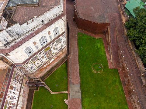 Aerial view of the historic Lahore Fort featuring intricate architectural tile work, lush green courtyards, and ancient red brick walls in Lahore, Punjab, Pakistan.