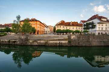 Fototapeta premium Architecturally elegant buildings on Ljubljanica River in central Ljubljana, Slovenia, on calm clear summer morning reflected in river's still water.