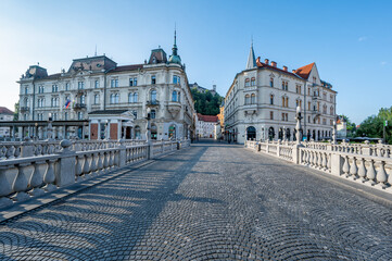 Fototapeta premium Architecturally elegant buildings from Triple Bridge over Ljubljanica River in central Ljubljana, Slovenia in early morning summer light.
