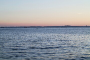 Obraz premium A peaceful view of a harbor waterway at dusk with distant vessels.