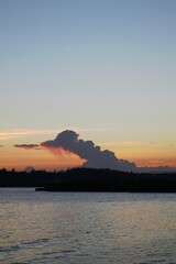 Fototapeta premium Sunset over a calm coastal harbor with dramatic cloud formations.