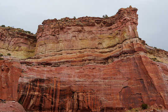 Massive layered sandstone cliffs in red, brown, and yellow tones reveal complex sedimentary history shaped by millions of years of erosion