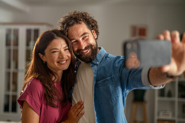 Obraz premium Happy smiling couple taking a selfie using smart phone at home