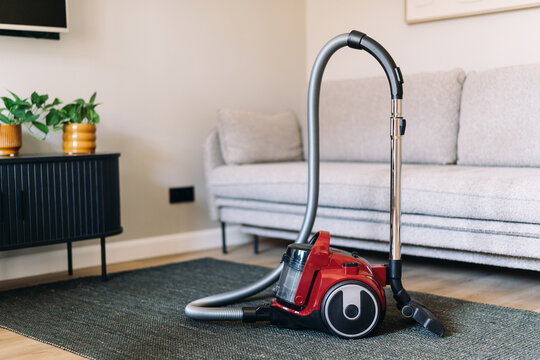 Washing vacuum cleaner in modern apartment on carpet floor