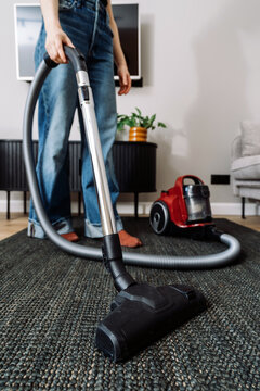 Woman vacuums the living room floor in a modern apartment space