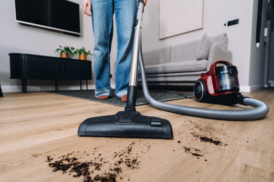 Woman cleans soil on the floor with vacuum cleaner