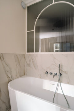White freestanding bathtub in modern marble tiled bathroom interior