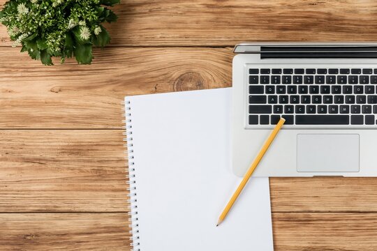 Workspace with a laptop notebook pencil and plant on a rustic wooden office desk