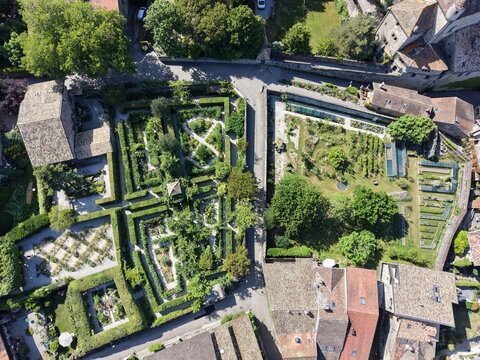 Aerial view of the Jardin des Cinq Sens with intricate hedge mazes, geometric garden beds, and stone pathways in the historic village of Yvoire, Auvergne-Rhone-Alpes, France.