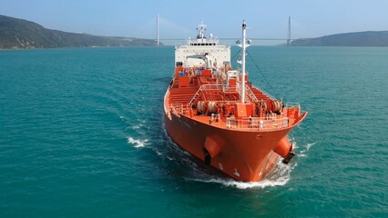 Large red oil tanker ship navigating through Bosphorus, creating a bow wave as it moves forward, with various deck equipment including anchor winches and a mast. Maritime navigation challenges © Faraways
