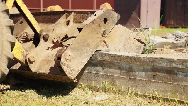 Powerful yellow loader bucket pushing and moving a large, heavy concrete slab across the ground at a construction or demolition site, showcasing the force and capability of earthmoving equipment