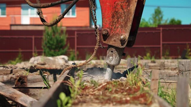 Hydraulic breaker demolishing concrete inside old wooden formwork in a residential yard, showing foundation removal, demolition equipment and site preparation.