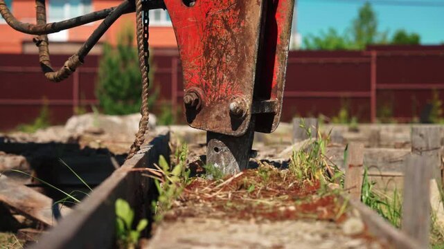 Heavy machinery with a hydraulic hammer breaking down reinforced concrete structures during demolition work
