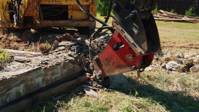 Close-up of a hydraulic breaker pressing against a reinforced concrete foundation with exposed rebar during residential demolition, showing structural removal, heavy equipment and site preparation.
