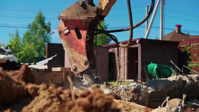 Powerful hydraulic jackhammer smashing reinforced concrete blocks on a construction site. Heavy machinery dismantling a building foundation. With dust and debris flying from the impact of the breaker