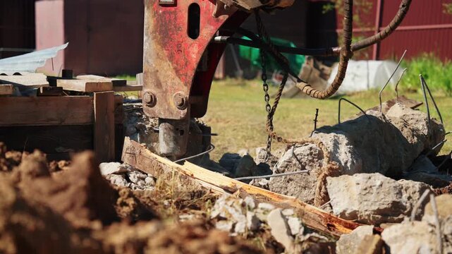 Close-up of a hydraulic breaker breaking a reinforced concrete foundation with exposed twisted rebar during residential demolition, showing structural removal, heavy equipment and site cleanup.