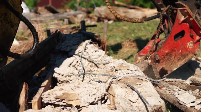 Heavy machinery with a hydraulic breaker attachment powerfully dismantling a reinforced concrete structure, shattering the material into debris and rubble at a demolition construction site