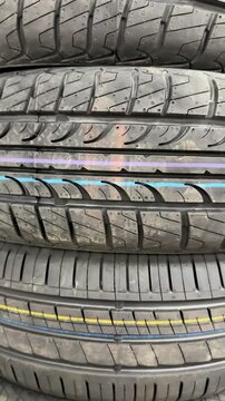 Stacked summer tires macro shot showing detailed tread patterns with colorful factory lines rubber texture multiple new passenger