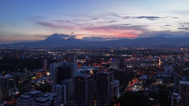 Vista de altura de Ciudad de Guatemala con rascacielos residenciales y luces urbanas de noche. Atardecer dram&aacute;tico y colorido sobre el horizonte de la Ciudad de Guatemala.