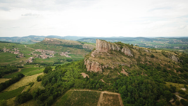 Aerial view of the Rock of Solutre, a limestone escarpment rising above lush green vineyards and rolling hills in Solutre-Pouilly, Bourgogne-Franche-Comte, France.