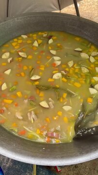 The initial stage of making *Asyura* porridge involves mixing all the ingredients and spices in a large wok and stirring the mixture continuously.