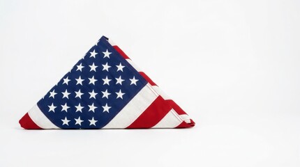 Fototapeta premium A neatly folded American flag displayed with stars and stripes on a plain white surface