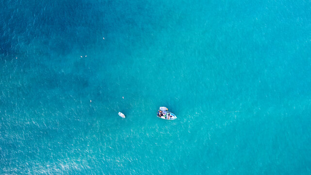 Aerial view of a small boat floating in the clear turquoise waters of the Pacific Ocean near the coast of Lima, Provincia de Lima, Peru.