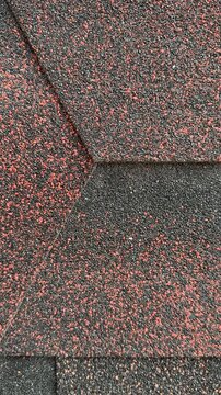 Close-up red hexagonal shingles texture, flexible asphalt roofing with coarse granules, overlapping pattern with subtle weathering