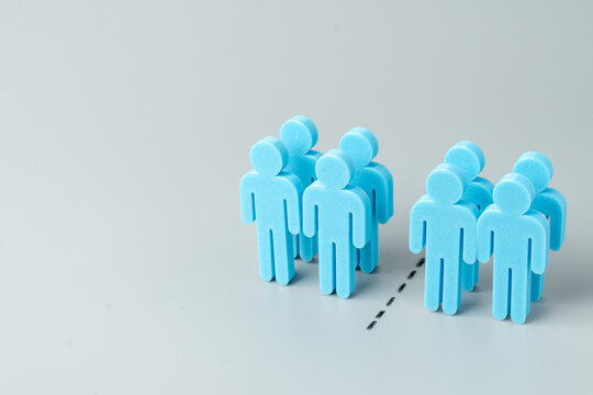Blue human figures divided into two separate groups on a gray background. Social division, market segmentation, border separation, or teamwork conflict concept. Copy space for text.