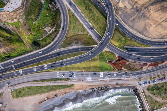 Aerial view of the Costa Verde highway interchange with multi-level roads, coastal cliffs, and the Pacific Ocean shoreline in Miraflores, Provincia de Lima, Peru.