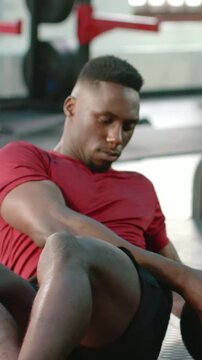 Vertical video: Rotating man in red shirt starting seated with medicine ball in gym, building core