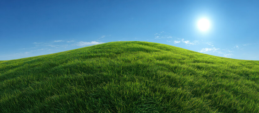 A lush green grass hill under a bright blue sky with sunlight shining, creating a serene natural landscape.
