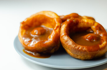Fototapeta premium Golden-brown Yorkshire puddings sit on a cool blue plate