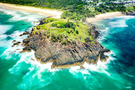 Aerial view of the rocky Norries Headland surrounded by turquoise ocean waves and sandy coastline at Cabarita Beach, New South Wales, Australia.