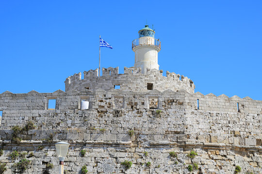 The medieval Fortress of Saint Nicholas with the 17th century lighthouse and Greek flag above on the Mandraki pier in Rhodes Town, on the island of Rhodes, Greece.
