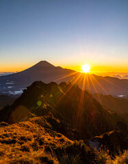 Obraz premium Sunrise over mountain peaks with rugged terrain and clear blue sky