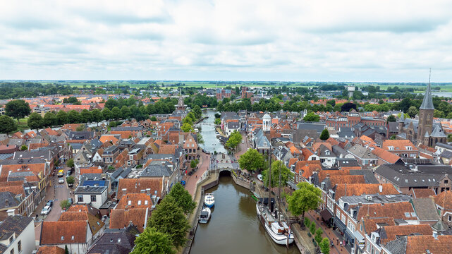 Aerial view of the historic town center featuring red-tiled rooftops, a central canal with moored boats, and a church spire, Dokkum, Friesland, Netherlands.