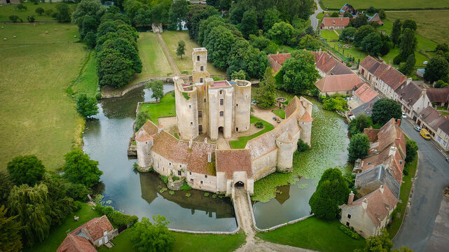 Aerial view of the historic Chateau de Sagonne surrounded by a moat, lush green gardens, and stone fortifications in the rural landscape of Sagonne, Centre-Val de Loire, France.