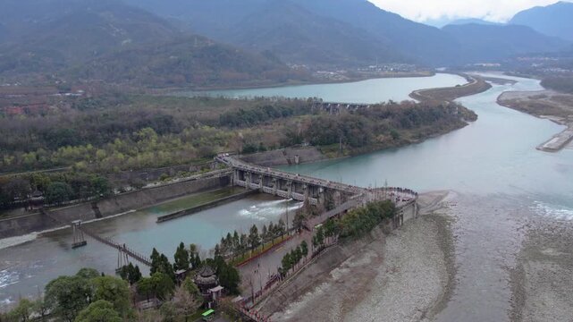 A panoramic view of an ancient water conservancy project spanning a river, surrounded by mountains and vegetation.