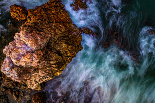 Aerial view of the rugged rock formations at Flynns Beach with crashing ocean waves creating white foam patterns in Port Macquarie, New South Wales, Australia.
