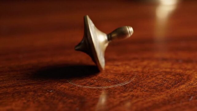 Brass Spinning Top Rotating on Wooden Table