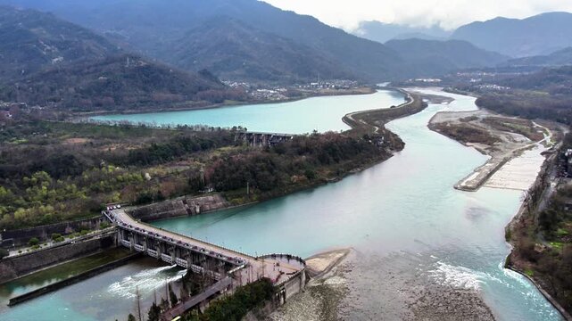 Aerial view of an ancient water conservancy project, with river channels, dams, and mountainous landscape around.