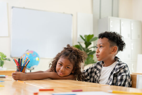 Young diverse students sitting together at a desk in a classroom, Education concept, happy multi-ethnic children learning in a modern school, Boy and girl students studying during a lesson