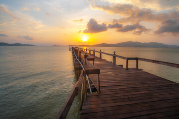 Obraz premium A wooden pier in the sea, in the evening as the sun is setting.