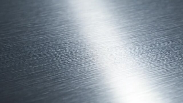 A close-up view of a metallic surface reflecting light with a beam shining on it.