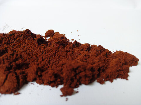 Pile of finely ground brown coffee powder on white background